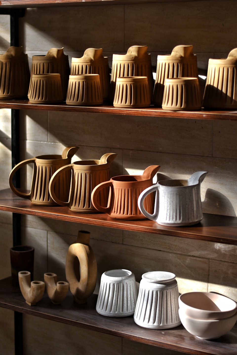 Ceramic pottery displayed on dark wooden shelves.